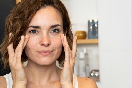 Una mujer poniéndose crema en la cara
